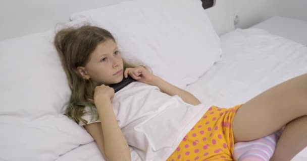 Matin au lit, fille enfant couché avec télécommande et regarder la télévision — Video