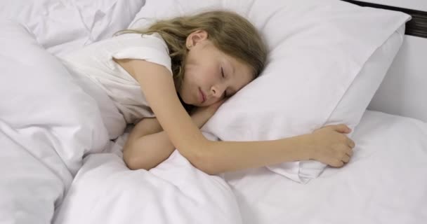 Girl child ten years old with long curly blond hair sleeping in white bed on pillow — Stock Video