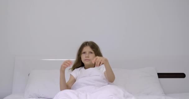 Niña durmiendo en una cama blanca. Despertando, tocando los ojos soñolientos — Vídeos de Stock