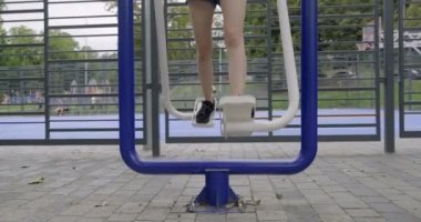 Açık hava spor simülatöründe bacak egzersizi yapan genç kız.