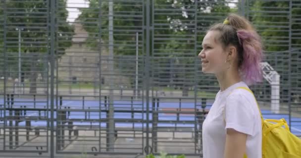 Girl teenager, student of 15 years walking near street basketball court — Stock Video