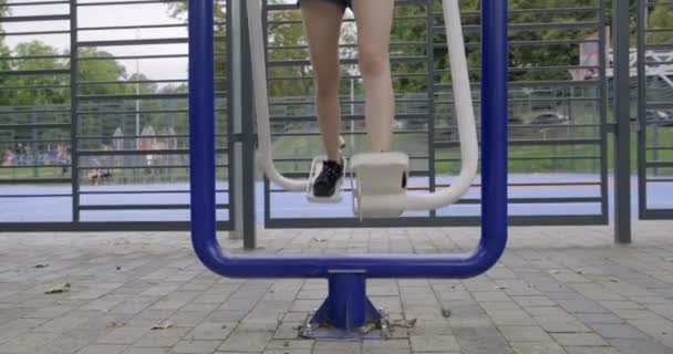 Adolescente faisant des exercices pour les jambes sur un simulateur de sport en plein air — Video