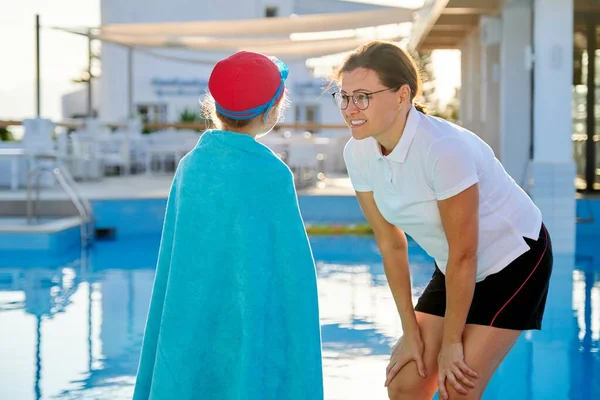 Madre e hija niño en gafas de sombrero para nadar con toalla cerca de la piscina — Foto de Stock