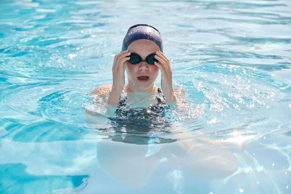 Лицо молодой женщины пловчихи в бассейне, девушка в кепке очки для плавания — стоковое фото