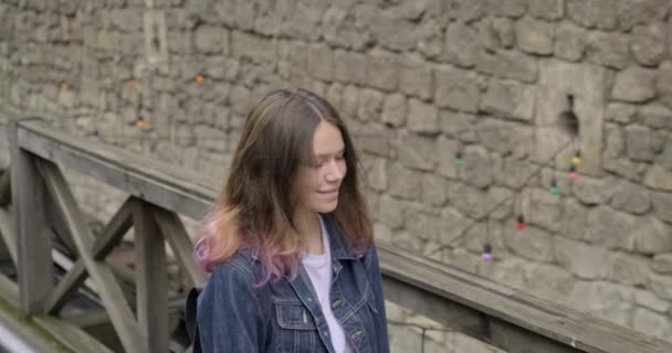 Sonriente chica adolescente con el pelo morado en chaqueta de mezclilla caminando en el casco antiguo turístico — Vídeo de stock