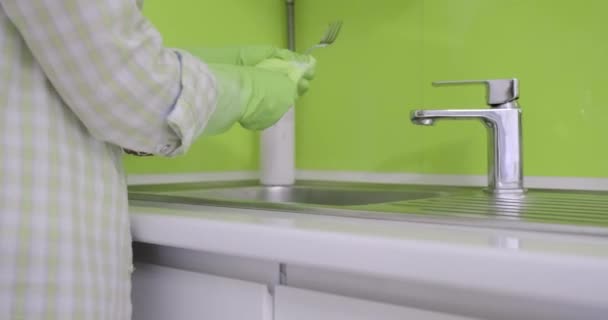 Mujer madura en guantes de goma lavando platos en la cocina con esponja con detergente — Vídeo de stock