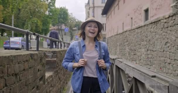 Sonriente mujer de mediana edad caminando en una vieja ciudad turística — Vídeo de stock