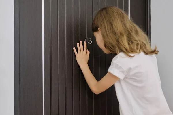 Lány gyermek néz a kukucskálóba a bejárati ajtón — Stock Fotó