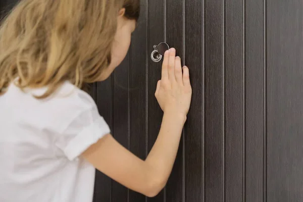 Girl child looking in the peephole at the front door — Stock Photo, Image