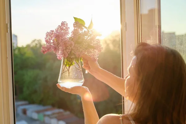 Bouquet of flowers lilac in jug in womans hand — Stock Photo, Image