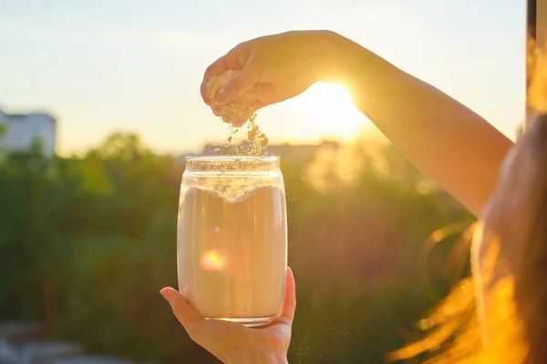 Flour in glass jar in womans hand, background sunset — Stock Photo, Image
