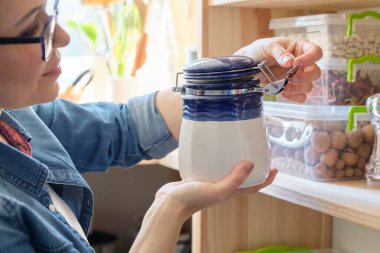 Mutfakta elinde kuru nane, yiyecek deposu ve kiler olan bir kadın var.