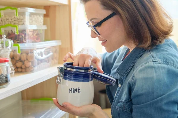 Mulher na cozinha com lata de hortelã seca, armazenamento de alimentos, despensa — Fotografia de Stock