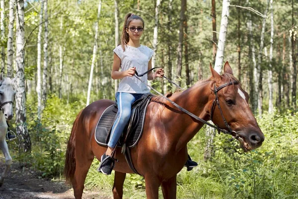 Adolescente menina montando um cavalo marrom, cavalgando para as pessoas no parque — Fotografia de Stock