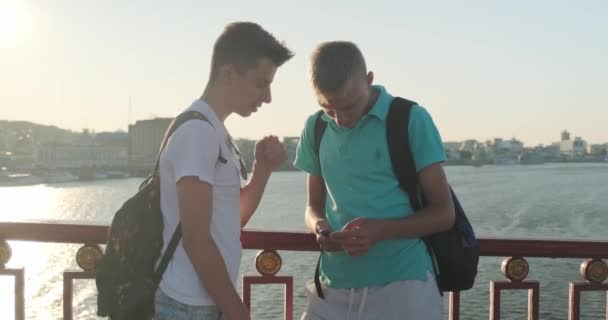 Twee vrienden tiener jongens met behulp van smartphone, praten en glimlachen — Stockvideo