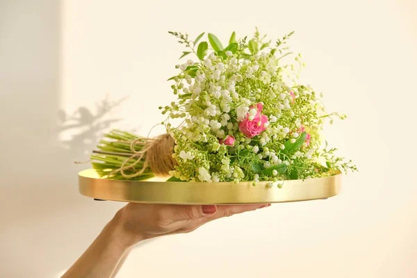 Bukett med färska vårblommor av rosa ros, liljekonvalj, viburnum grenar och spirea på brickan — Stockfoto