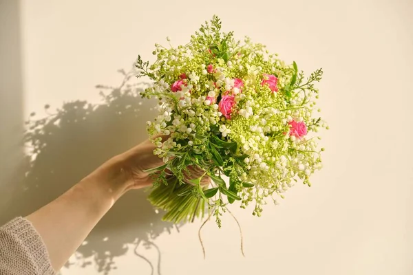 Belo buquê fresco de lírio das flores do vale, rosa rosa, ramos verdes na mão da mulher — Fotografia de Stock