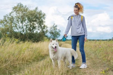 Beyaz köpekli güzel kız, iri yarı evcil hayvanla yürüyen genç kız.