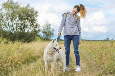 Beyaz köpekli güzel kız, iri yarı evcil hayvanla yürüyen genç kız.