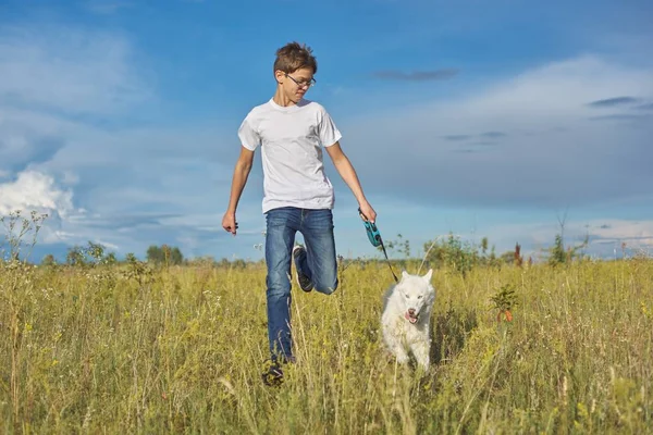 Mode de vie sain actif, adolescent garçon courir avec chien blanc husky — Photo