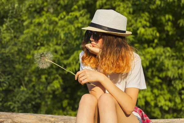 Menina triste sentado na natureza com um dente-de-leão fofo, adolescente infeliz grave — Fotografia de Stock