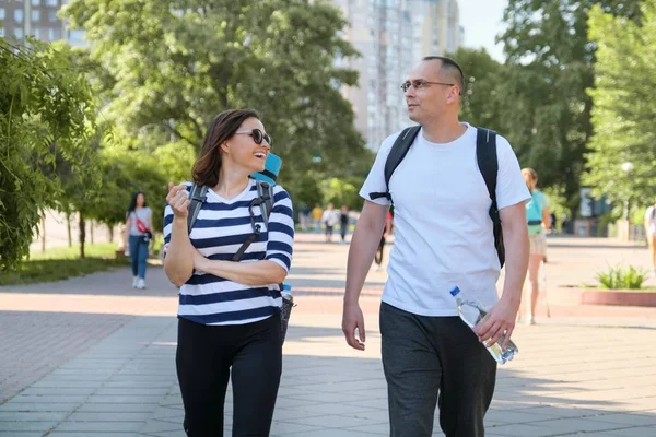 Pareja de mediana edad en ropa deportiva caminando y hablando en el parque —  Fotos de Stock