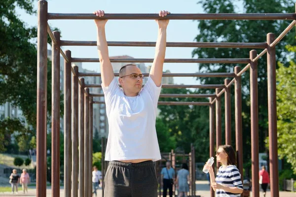 Middle-aged man doing pull up exercise on horizontal bar outdoor — Stock Photo, Image