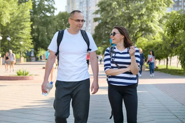 Pareja de mediana edad en ropa deportiva caminando y hablando en el parque —  Fotos de Stock