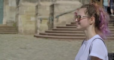 Güzel, gülümseyen, sırt çantalı genç bir kız eski bir turistik şehirde yürüyor.