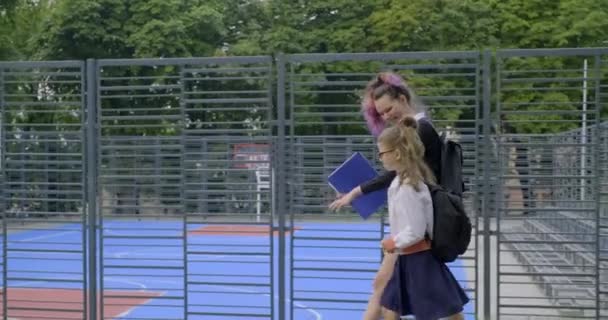 Δύο αδερφές πάνε σχολείο, παιδιά με σχολική στολή με σακίδια. — Αρχείο Βίντεο