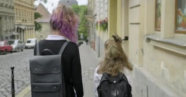 Duas meninas irmãs indo para a escola com mochilas, visão traseira — Vídeo de Stock