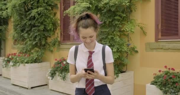 Beautiful student teenager girl with smartphone reading and writing text message — 图库视频影像