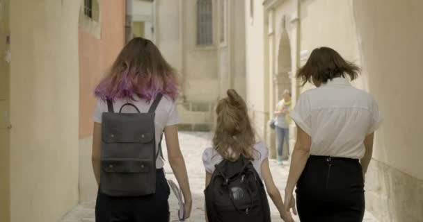 Мать и две дочери школьницы, идущие вместе, вид сзади — стоковое видео