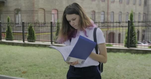 Girl student with school papers reading and studying, outdoor — 图库视频影像
