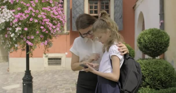 Moeder en dochter relatie, schoolmeisje met behulp van een outdoor telefoon met moeder — Stockvideo