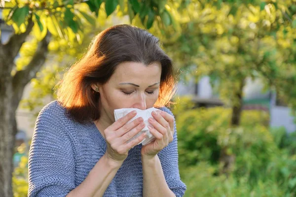 Mendile hapşıran olgun bir kadın, polene alerjisi, soğuk algınlığı. — Stok fotoğraf