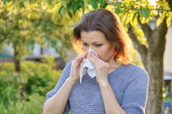 Alergias estacionales, mujer con toallita nasal, estornudos, limpieza nasal al aire libre —  Fotos de Stock