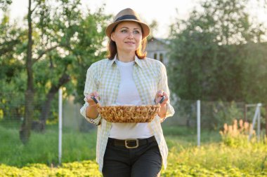 Çayırda yumurta sepeti olan olgun bir kadının taşralı portresi.