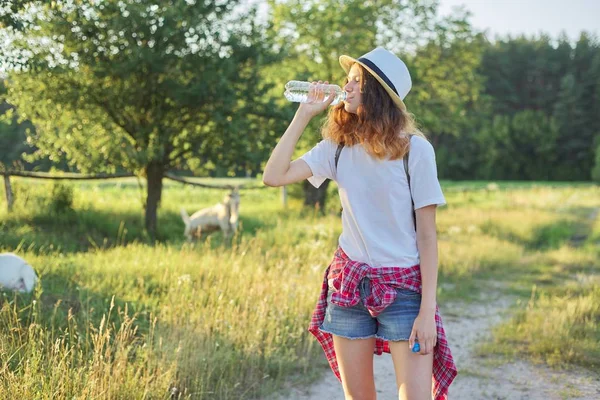 Jovem adolescente andando menina bebendo água de garrafa — Fotografia de Stock