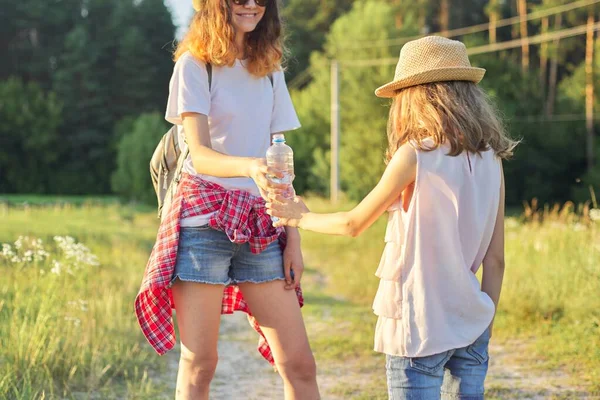 Děti dvě dívky sestry s lahví vody v horkém letním dni v přírodě — Stock fotografie