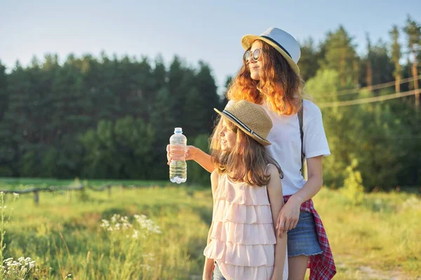 Niños dos niñas hermanas con botella de agua en el caluroso día de verano en la naturaleza — Foto de Stock