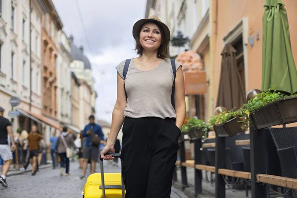 Viajando sorrindo mulher madura turista de chapéu com mochila e mala andando — Fotografia de Stock