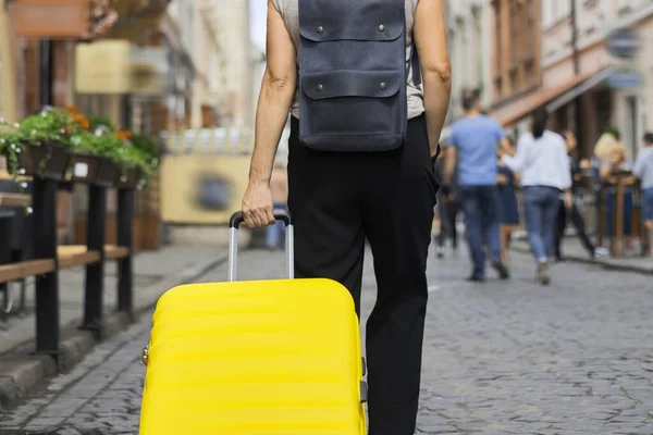 Luggage ταξιδιωτικός τουρισμός έννοια, closeup κίτρινο βαλίτσα στο χέρι της γυναίκας με τα πόδια — Φωτογραφία Αρχείου