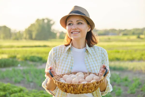 Rustikt porträtt av mogen kvinna med korg av ägg på ängen — Stockfoto