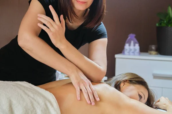 Mulher madura deitada na mesa de massagem e recebendo massagem médica nas costas — Fotografia de Stock