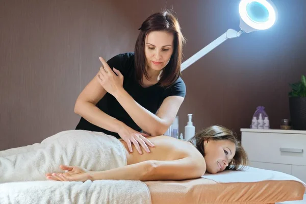 Volwassen vrouw liggend op massage tafel en het ontvangen van medische rug massage — Stockfoto