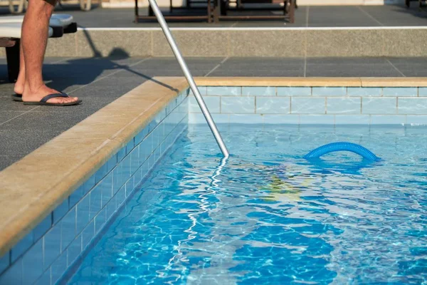 Limpieza masculina piscina al aire libre con tubo de vacío bajo el agua —  Fotos de Stock