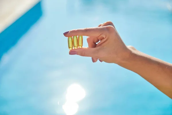 Солнечные золотые капсулы с витамином D в женской руке — стоковое фото