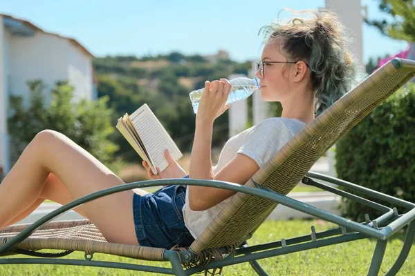 Девочка отдыхает на свежем воздухе, читает книги и пьет воду — стоковое фото