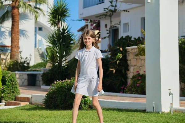 Серйозна розлючена дівчинка 9 років у білій сукні, що йде — стокове фото
